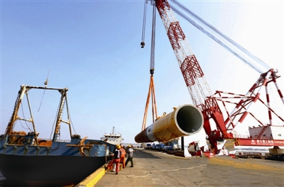 8月11日，投資12億元由江蘇長鑫龍海上裝備公司自主研發(fā)并生產(chǎn)的首套36根鋼管樁，通過江蘇大豐港直運如東海上風電工地。圖為吊裝鋼管樁現(xiàn)場